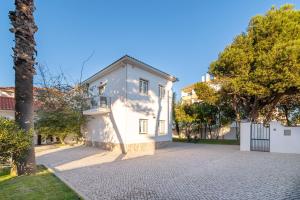 a white house with a tree next to a driveway at Silver Seahorse Garden Retreat in Peniche