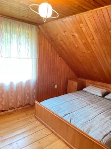 a bed in a wooden room with a window at Три смерічки in Beloberëzka