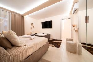 een witte slaapkamer met een bed en een televisie bij Desiree Luxury House- vasca idromassaggio in Catania