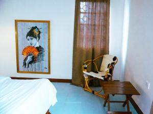 ein Schlafzimmer mit einem Bett, einem Stuhl und einem Gemälde in der Unterkunft Garden Villa 5BR Home Near Road,Nature and City Life in Arusha