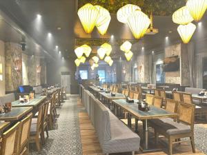 a restaurant with long tables and chairs and chandeliers at Shelter Suites - Formerly known as Fisco The Hub Link in Mumbai