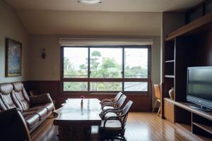Una sala de estar con una mesa y sillas y un televisor. en Condominium Takabatake, en Nara