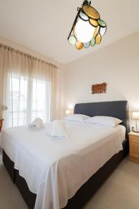 a bedroom with a large white bed with a chandelier at Thanos and Sofia by RentalsPro - Dionisou Halkidiki in Paralia Dionysiou