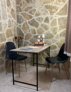 a table and two chairs in front of a stone wall at Seaside pearl in Lygia +6 photos