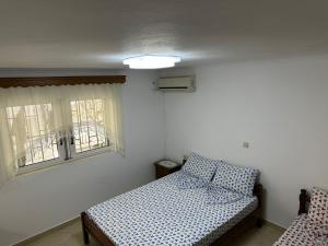 a bedroom with a bed and two windows at Pandora Apartament in Sarandë
