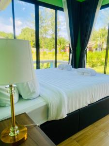 ein Schlafzimmer mit einem Bett mit einer Lampe und einem Fenster in der Unterkunft Leelavadee Villa Sea Views in Tha Sala