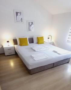a large white bed in a white room with yellow pillows at Apartments Platz in Mostar +34 photos