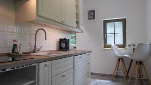 a kitchen with white cabinets and a sink at Gara Cottage Private escape with modern comfort and spacious covered terrace in Garabonc