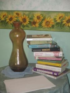 una pila de libros sentados en una mesa con un jarrón en Ospitalità rurale La Svizzera, en Agliè