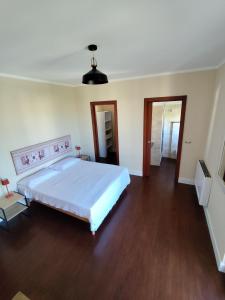 ein Schlafzimmer mit einem großen weißen Bett und Holzböden in der Unterkunft Casa vacanze da Alice in Alghero