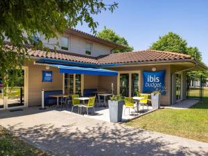 Un restaurante con mesas y sillas frente a un edificio. en ibis budget Bourg en Bresse, en Bourg-en-Bresse