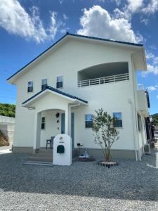 淡路アオイカゼ的一栋白色的房子，前面有一棵树