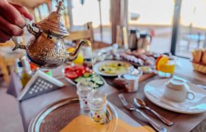 a person is holding a tea kettle on a table at Staying Desert Luxury Camp in Merzouga