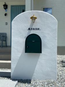 ein weißes Gebäude mit einer Tür in der Mitte in der Unterkunft アオイカゼ in Awaji