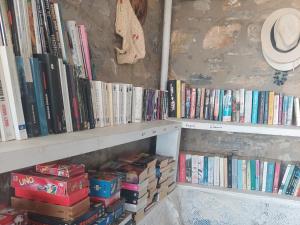 a book shelf filled with books and a hat at Anatoli Studios in Schinoussa