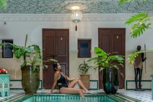 una mujer sentada en el borde de una piscina en Riad Les Dunes And SPA, en Marrakech