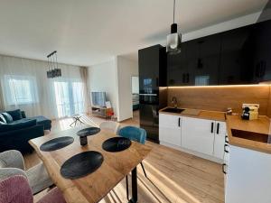 a kitchen and a living room with a wooden table at Nexus apartman in Siófok