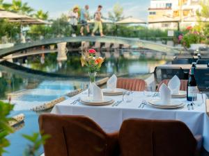 a table with plates and a vase of flowers on top of a pool at Gloria Palace Hotel & SPA in Golem +42 photos