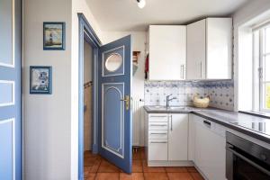a kitchen with white cabinets and a blue door at Annes Cottage 3 in Oevenum +17 photos