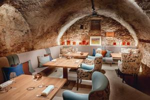 a restaurant with wooden tables and chairs and a stone wall at Mount Med Resort in Oberau