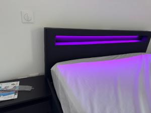 1 dormitorio con 1 cama con luz morada en Royal appart city 1, en Calais