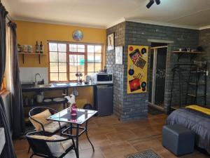 a living room with a table and a kitchen at Meadow View Retro Accommodation in Wakkerstroom