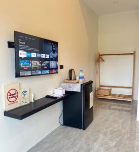 a room with a tv on the wall with a refrigerator at บ้านต้นลมสุวรรณภูมิ Baantonlom suvarnabhumi in Ban Khlong Thewa