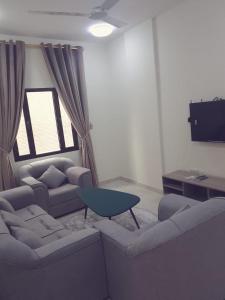 a living room with two couches and a blue table at Golden Seasons Furnished Apartment 7 in Salalah +7 photos