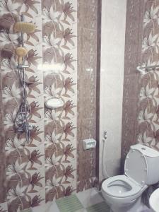 a bathroom with a toilet and a flower wallpaper at Golden Seasons Furnished Apartment 7 in Salalah