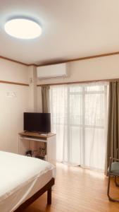 a bedroom with a bed and a tv and a window at Skytree Residence 錦糸町 駅から600M徒歩8分 in Tokyo