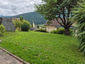 a green yard with a tree and a house at Gruber Alexandra, Appartement mit Lungaucard in Sankt Michael im Lungau