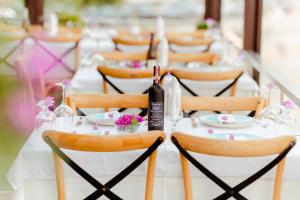 ein langer weißer Tisch mit Stühlen und einer Flasche Wein in der Unterkunft Rea Boutique Hotel in Himarë