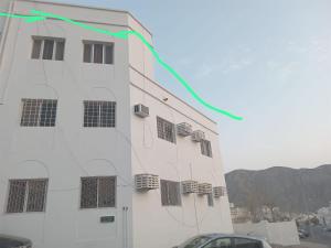 una cometa volando en el aire junto a un edificio en مسقط, en Maţraḩ