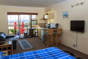 een kamer met een bed en een keuken met een televisie bij Bikini Beach Villas in Gordonsbaai