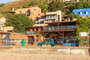 ein Haus mit einem blauen Auto vor einem Strand in der Unterkunft Bikini Beach Villas in Gordonʼs Bay