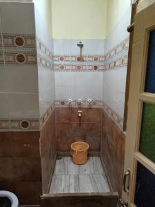 a bathroom with a bucket on the floor of a shower at The Travellers Cup Fort Stay in Jaisalmer