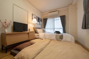 Una habitación de hotel con dos camas y un televisor de pantalla plana. en ぱんだホステル岩谷, en Tokio