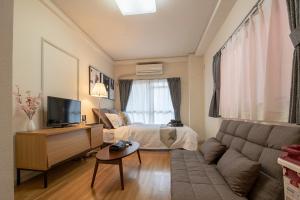 una sala de estar con un sofá y una cama en ぱんだホステル岩谷, en Tokio