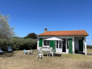 a small green and white house with a table and chairs at Maison sur la Mer - FrontSea in Angoulins-sur-Mer