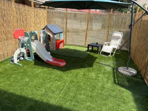un cortile con parco giochi con scivolo e ombrellone di Sole Apartment Livorno a Livorno