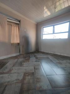 an empty room with a large window and a room with a floor at Self service catering cute and comfy nestled in the Center of Lenasia in Lenasia