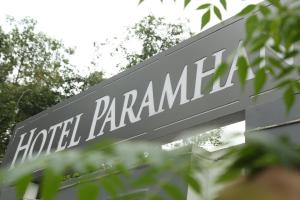 瑞诗凯诗Paramhans Hotel的一块写着“帕拉曼卡酒店”的牌子，坐落在几棵树后面
