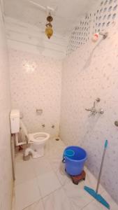 a bathroom with a toilet and a blue bucket at Dylan Cafe And Guest House in Jodhpur