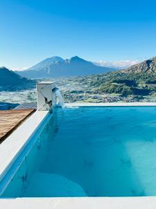 a pool with blue water and mountains in the background at Mai camp in Baturaja