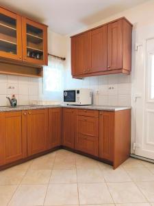 a kitchen with wooden cabinets and a microwave at Green Garden Seaside Apartment in Chios