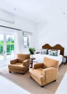 a bedroom with a bed and two chairs at Huguenot House in Franschhoek +1 photo