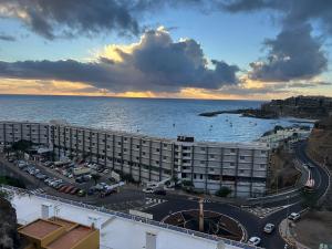 a large hotel with a parking lot next to the ocean at Granada I Apartment- Patalavaca in Patalavaca