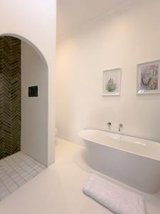 a white bathroom with a tub and a shower at Huguenot House in Franschhoek