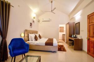 a bedroom with a bed and a blue chair at Close2C By The Arks Villa in Anjuna +89 photos