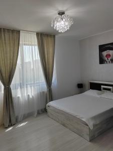 a bedroom with a large bed and a chandelier at DML Apartment in Mamaia Nord